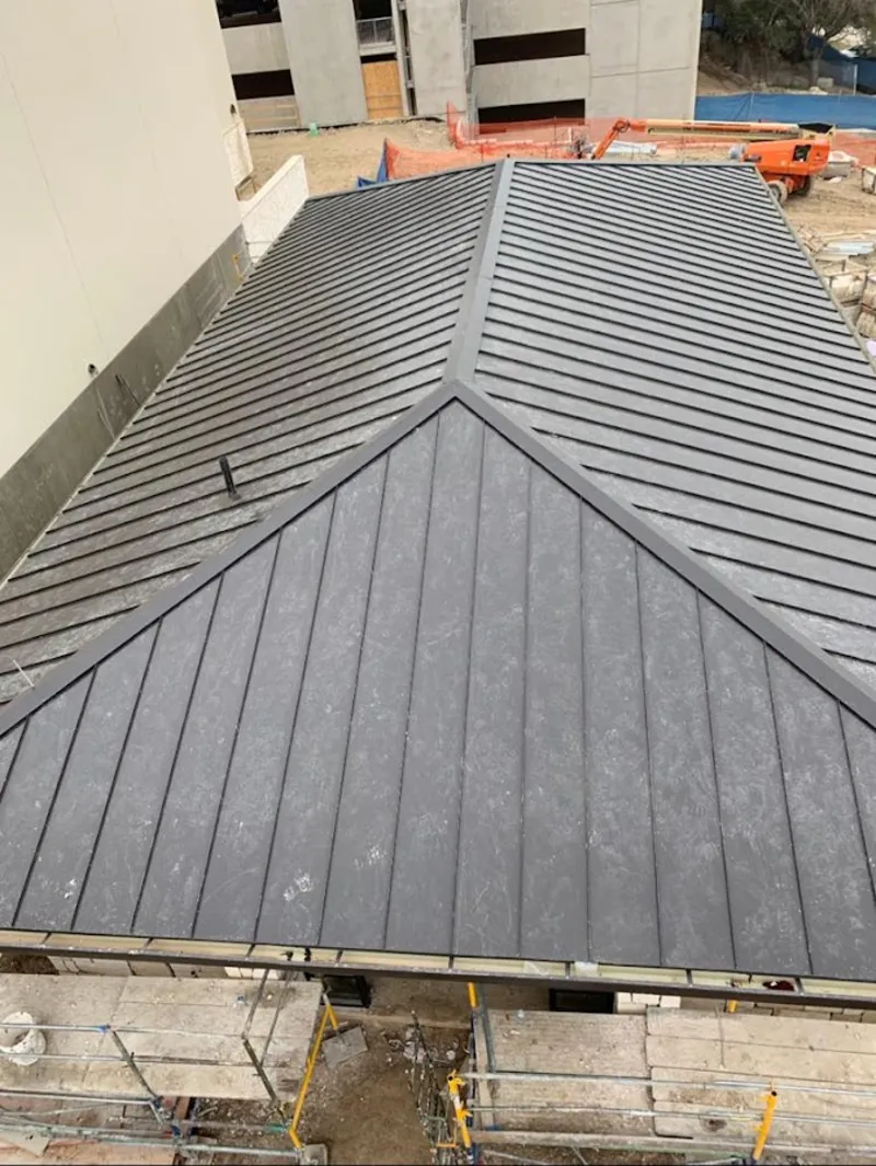 Commercial metal roof construction with crane equipment in Aztec