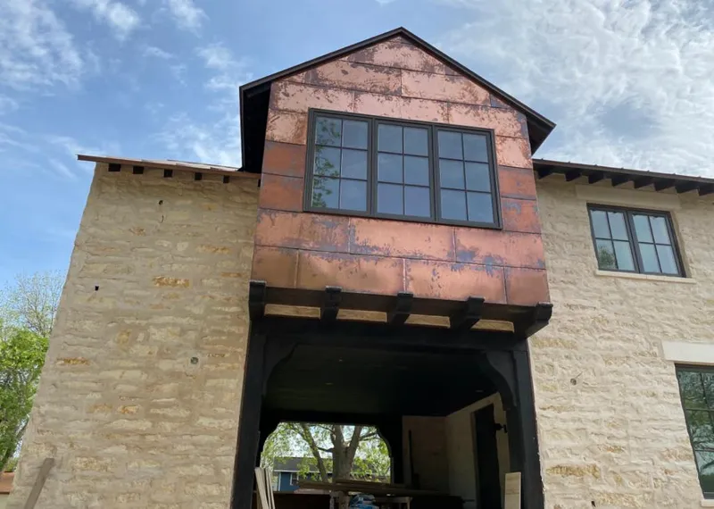 Copper metal panel facade on a stone building for Roof Repair in Aztec